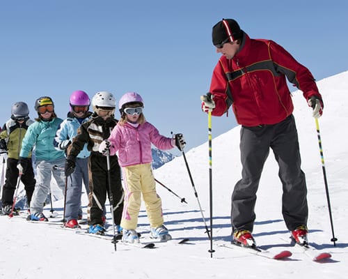Ski instructor leading children on the slopes.