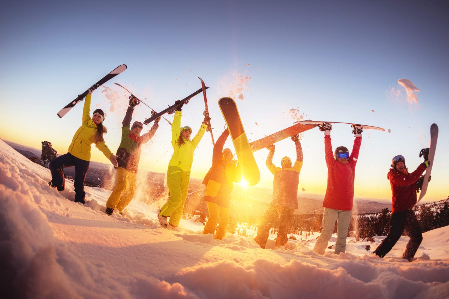 Skiers and snowboarders celebrating and jumping for joy.